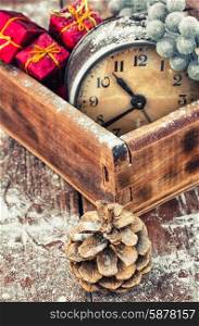 retro arrangement for Christmas with an old alarm clock. outdated watch in wooden box on the background of Christmas decorations and pine cones.