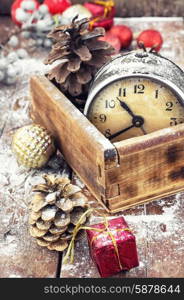 retro arrangement for Christmas with an old alarm clock. outdated watch in wooden box on the background of Christmas decorations and pine cones.Photo tinted.