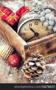 retro arrangement for Christmas with an old alarm clock. outdated watch in wooden box on the background of Christmas decorations and pine cones.Photo tinted.