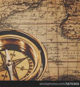 Retro brass compass over antique paper map, adventure backgrounds