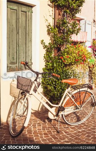 Retro bycicle in Italy. White vintage bicycle with basket on vintage house wall in Italy