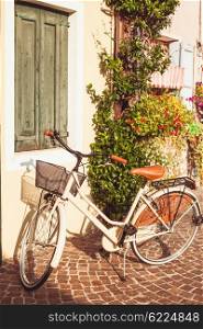 Retro bycicle in Italy. White vintage bicycle with basket on vintage house wall in Italy