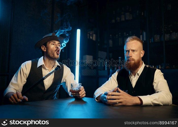 Retro dressed gangsters smoking hookah in bar. Serious handsome guys having business meeting while spending time at nightclub. Stylish gangsters smoking hookah in bar having business meeting