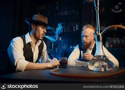 Retro dressed gangsters smoking hookah in bar. Serious handsome guys having business meeting while spending time at nightclub. Stylish gangsters smoking hookah in bar having business meeting