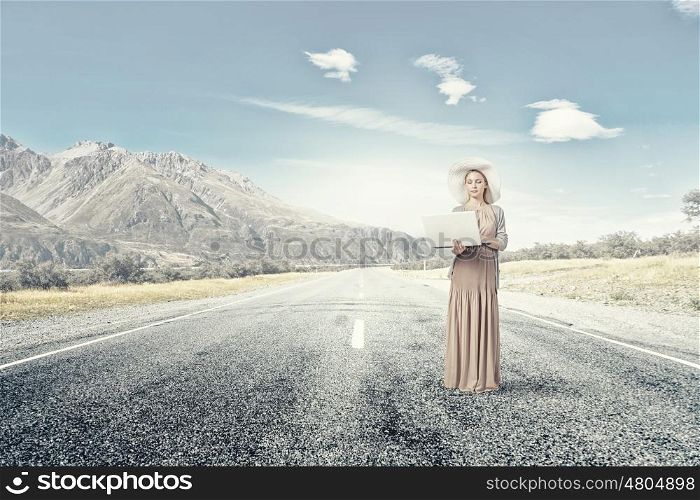 Retro girl with laptop. Young lady in dress and hat outdoor with laptop in hands