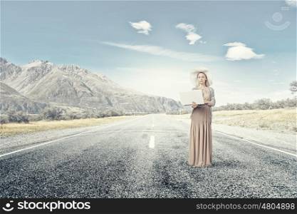 Retro girl with laptop. Young lady in dress and hat outdoor with laptop in hands