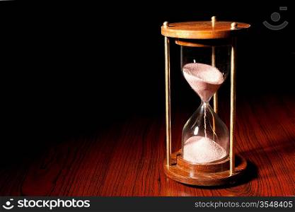 Retro hourglass (sand timer) on wooden table