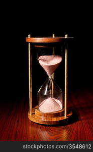 Retro hourglass (sand timer) on wooden table