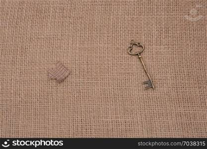 Retro key and an arrow cut out of brown paper on canvas