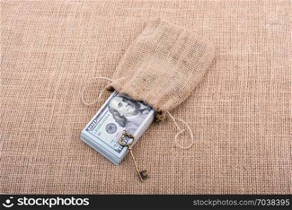 Retro key and bundle of US dollar in a sack on a canvas