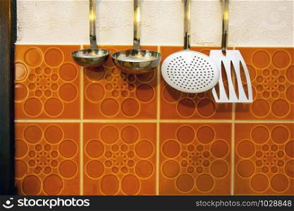 Retro kitchen tools hangs on vintage orange tiled wall background closeup. Retro kitchen tools hangs on vintage orange tiled wall background