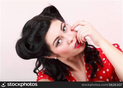Retro look pin-up brunette girl flirting her finger touch her mouth studio shot pink background