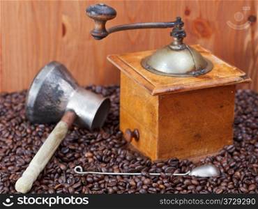 retro manual coffee grinder , copper pot, spoon on many roasted coffee beans