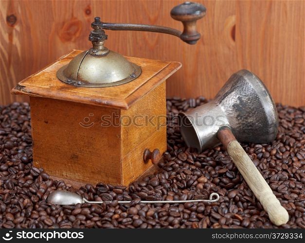 retro manual coffee mill , copper pot, spoon on many roasted coffee beans
