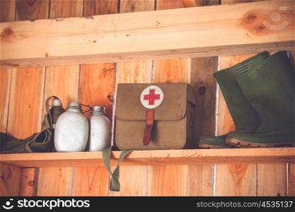 Retro medic equipment on an old wooden shelfe with boots and water bottles