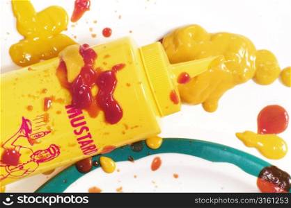 Retro mustard bottle with mustard and tomato ketchup everywhere