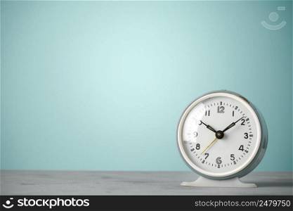 Retro old classic round alarm clock on desk blue vintage color background with copy space