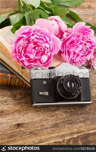 retro photo camera. old photo camera with books and fresh peony flowers