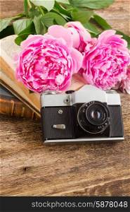 retro photo camera. old photo camera with books and fresh peony flowers