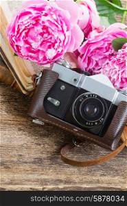 retro photo camera. old photo camera with books and peony flowers