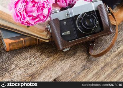 retro photo camera. retro photo camera with books and fresh pink peony flowers