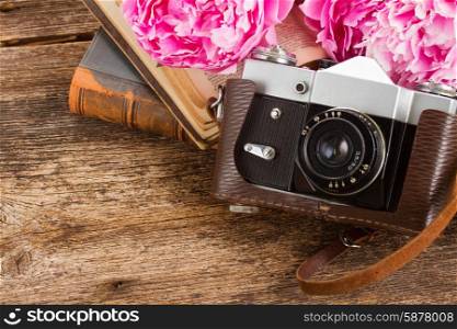 retro photo camera. retro photo camera with books and peony flowers on wooden table