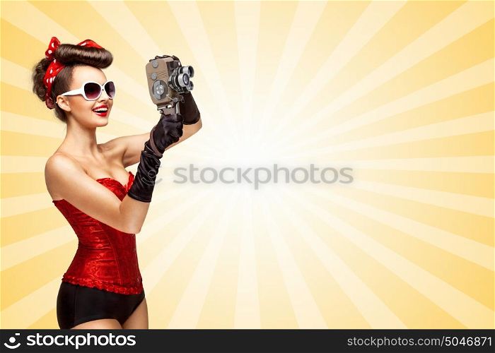 Retro photo of a glamorous pin-up girl with an old vintage cinema 8 mm camera shooting a movie on colorful abstract cartoon style background.