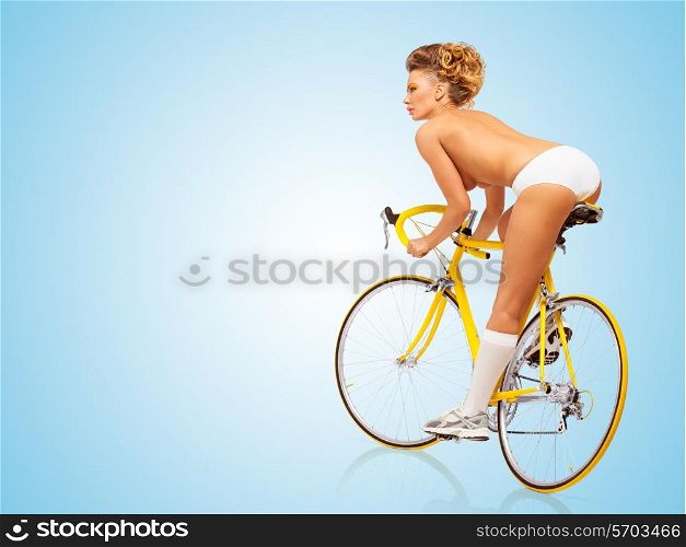 Retro photo of a nude sexy pin-up girl in white erotic panties riding a yellow racing bicycle on blue background.