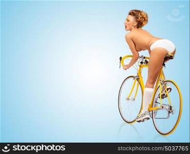 Retro photo of a nude sexy pin-up girl in white panties riding a yellow racing bicycle on blue background.