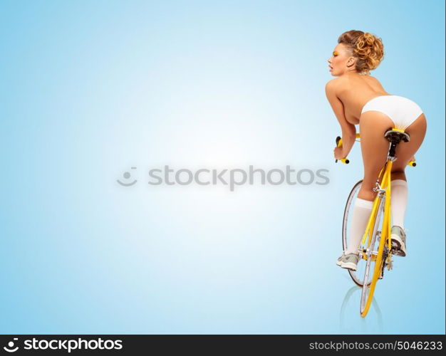 Retro photo of a nude sexy pin-up girl in white panties riding a yellow racing bicycle on blue background.