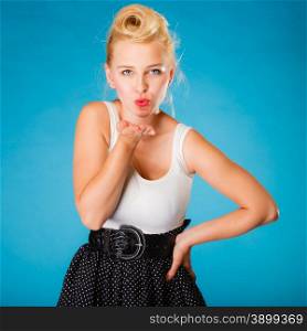 Retro pin up girl style. Young attractive woman sending hand kiss. Studio shot on blue background.