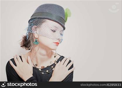 Retro portrait of a beautiful young girl wearing a hat with a veil on a white background