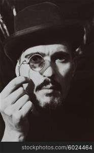 Retro portrait of an adult man wearing a hat and holding a pince-nez