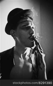 Retro portrait of beautiful young man in a hat with a cigarette