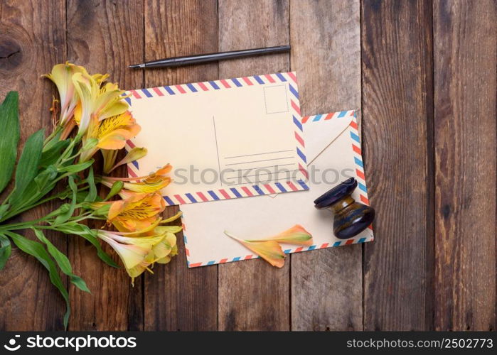 Retro postcard with envelope, stamp and flowers on vintage wooden table still life