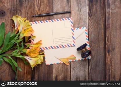 Retro postcard with envelope, stamp and flowers on vintage wooden table still life