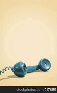 Retro rotary phone handset on a vintage yellow background in a vertical format with copy space and room for text