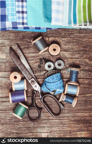 Retro scissors, textile and sewing threads on the wooden table