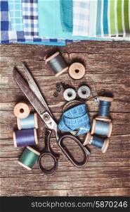 Retro scissors, textile and sewing threads on the wooden table