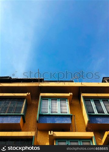 Retro style architecture Yellow building facade with green window against blue sky