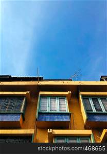 Retro style architecture Yellow building facade with green window against blue sky