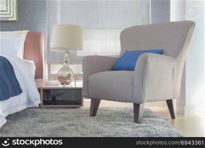 Retro style armchair with pillow next to bed in modern interior bedroom