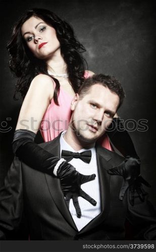 Retro style attractive fashionable couple in love, rich gangster with charming woman on black background
