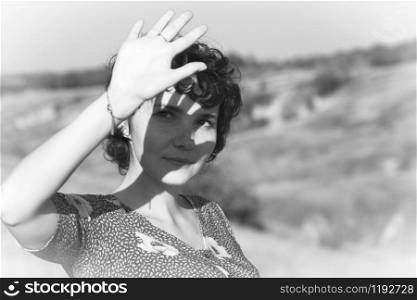 retro style. girl covers her face from the sun with her hand