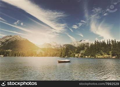 Retro style image of alpine mountain lake at sunny day