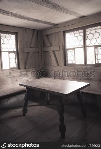 Retro style image with monochrome settings of an aged dining room interior with wooden furniture, walls and floor, depicting the rural life in medieval times.