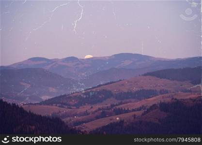 Retro style photo of moonrise over mountains hills