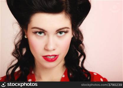 Retro style. Portrait of stylish young woman on pink. Face of brunette girl with pinup hairstyle and makeup.