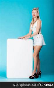 Retro style sexy blonde woman in full length with blank presentation board. Girl holds banner sign billboard copy space for text. Vivid blue background.