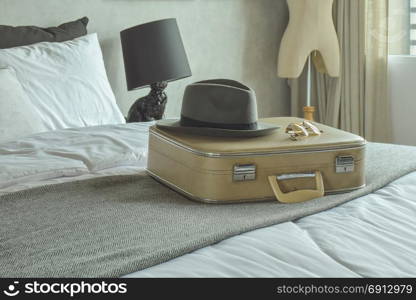 Retro style travel bag, hat and sunglasses on bed in hotel guestroom